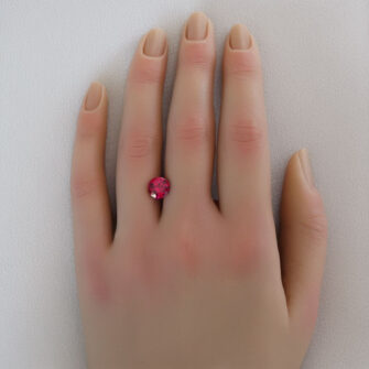 A lab-created ruby cut in a custom round design, shown on a woman's hand.