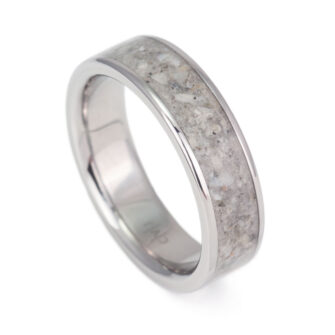 Photograph of a titanium ring, its band highlighted by a mesmerizing beach sand inlay.