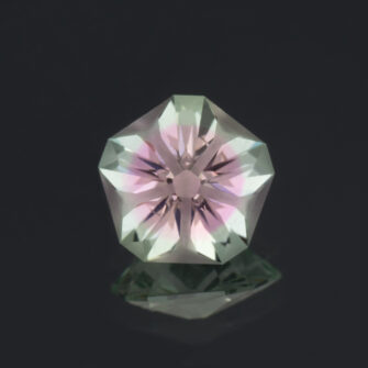 An image of a Hanami cut bi-color lab-created sapphire in green and pink.