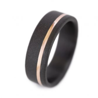 A black zirconium ring with an offset 14k rose gold inlay.