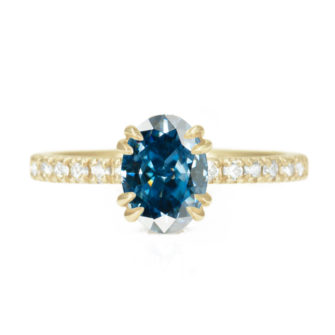 An image of a blue oval moissanite engagement ring in 14k yellow gold.