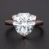 A large lab-created white sapphire engagement ring shines brightly in its meticulously crafted 14k rose gold setting.