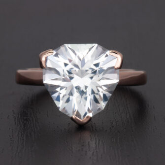 A large lab-created white sapphire engagement ring shines brightly in its meticulously crafted 14k rose gold setting.