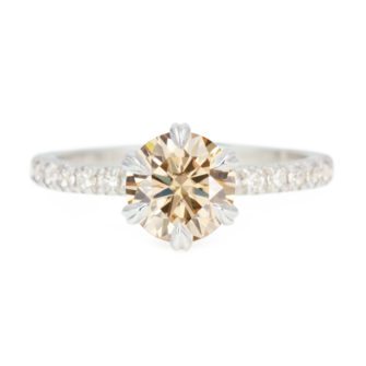 A picture of a champagne moissanite engagement ring with lab-grown diamond pavé setting.