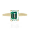 An image of a 14k yellow gold green moissanite engagement ring.