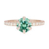 An image of a green moissanite engagement ring with a pavé half eternity band.