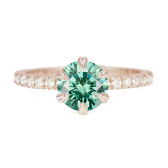 An image of a green moissanite engagement ring with a pavé half eternity band.