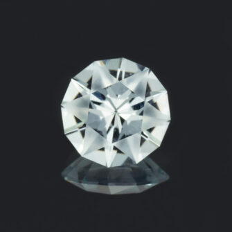 A closeup of a round aquamarine gemstone, cut with frosted main facets.