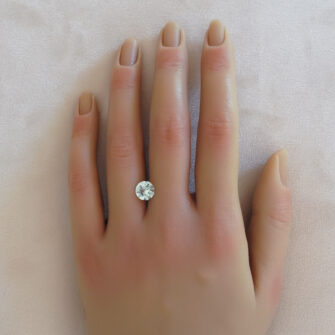 A light aquamarine gemstone on a woman's hand.