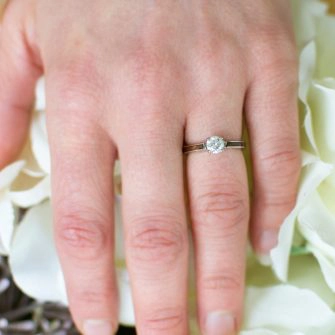 A lower profile wooden engagement ring pictured from above on a women's finger