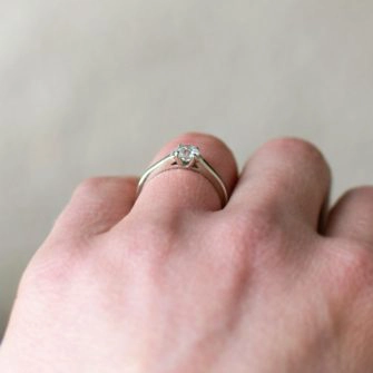 A low profile wood engagement ring shown on a women's ring finger