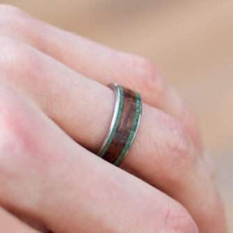 Our bubinga and jade wood and metal ring displayed on a finger, showcasing its sophisticated and natural design.
