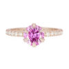 A picture of a rose gold pink moissanite engagement ring made with a pavé half eternity band.