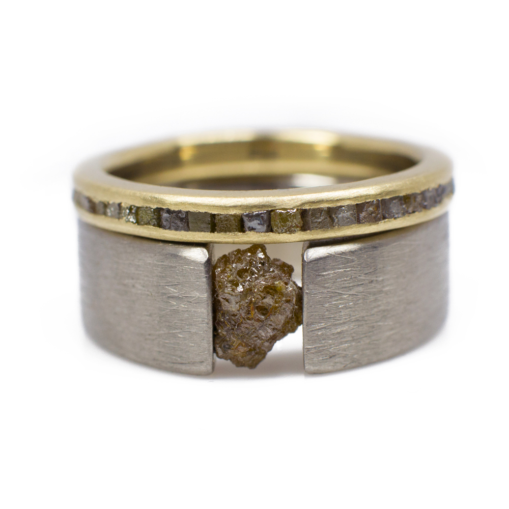 Two rough diamond rings. The first an inlaid eternity band in 14k gold with diamond cubes; the second, a tension set titanium ring.