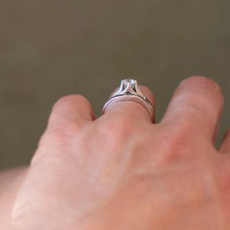 A profile view of a wooden bridal set shown on a women's finger