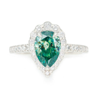 An image of a white gold moissanite engagement ring with a green pear cut center stone.