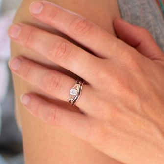 A wooden engagement ring and matching wedding band shown on a bride's ring finger