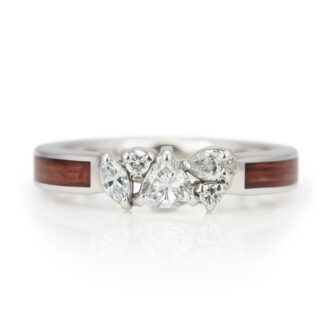 A product image of a wood and diamond engagement ring, featuring a diamond cluster.