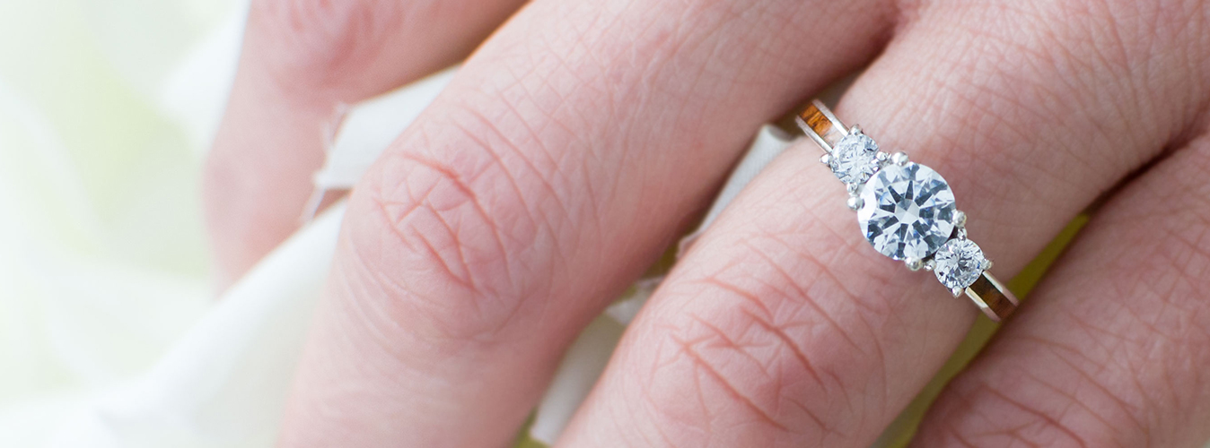 An image of a wood engagement ring on a woman's hand.